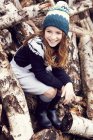 Portrait of young girl, sitting on log pile — Stock Photo
