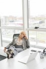 Скучная взрослая деловая женщина с ногами на столе в офисе — стоковое фото