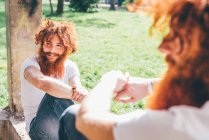 Молоді чоловіки хіпстер близнюки з червоними бородами сидять на парковій стіні — стокове фото