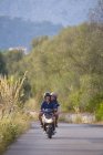 Young couple riding moped on rural road, Majorca, Spain — Stock Photo
