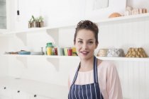 Portrait of young woman in kitchen looking at the camera — Stock Photo