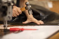 Mann hämmert Reißverschluss an Jacke in Lederjacke Hersteller, Nahaufnahme — Stockfoto