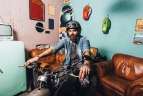 Портрет взрослого мужчины в комнате, сидящего на мотоцикле — стоковое фото