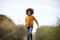 Жінка біжить вниз трав'янистою дюною — стокове фото