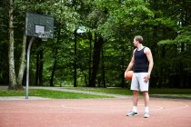 Young male basketball player looking over his shoulder at  basketball hoop — Stock Photo