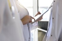 Женщины-врачи среднего звена используют цифровой планшетный сенсорный экран в больнице — стоковое фото