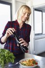 Жінка приправляє миску з макаронами на кухні — стокове фото