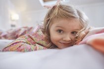Menina deitada na cama, foco em primeiro plano — Fotografia de Stock