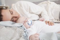 Madre con bebé niño durmiendo en la cama - foto de stock