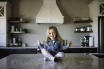 Portrait de fille assise jambes croisées sur le comptoir de la cuisine — Photo de stock