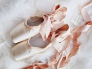 Ballet slippers with ribbons on fluffy plaid — Stock Photo