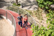 High angle view of running couple running up footbridge, Dubai, United Arab Emirates — Stock Photo