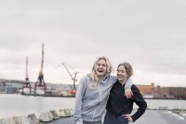 Two exhausted female running friends on dockside — Stock Photo