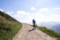 Vista traseira do ciclista ciclismo na pista de terra nas montanhas — Fotografia de Stock