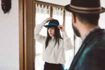 Young man waiting for woman trying on hat — Stock Photo
