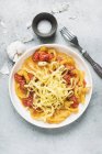 Pasta tagliatelle with cherry tomato sauce and garlic on white plate — Stock Photo