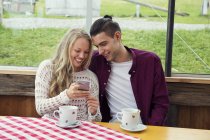 Junges Paar schaut sich Smartphone-Update im Café an — Stockfoto