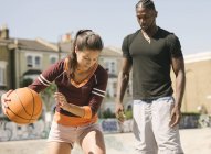 Femme et jeune homme pratiquant le basket dans un skatepark — Photo de stock