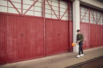 Молодий чоловік у міському районі підстрибуючи баскетбол, Брістоль, Великобританія — стокове фото