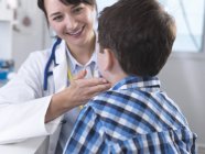 Doutor verificando se há glândulas inchadas no pescoço do menino — Fotografia de Stock