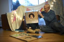 Uomo anziano mettere robot costume su nipote — Foto stock