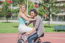 Feliz casal na bicicleta no parque juntos — Fotografia de Stock