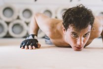 Man doing press ups and looking away in gym — Stock Photo