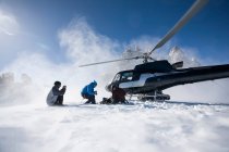 Tres snowboarders masculinos que salen en helicóptero, Trient, Alpes suizos, Suiza - foto de stock