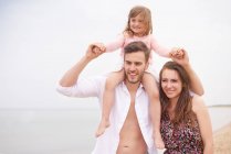 Familie spaziert am Strand, Tochter sitzt auf den Schultern des Vaters — Stockfoto