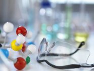 Защитные очки и молекулярная модель на лабораторной скамейке — стоковое фото