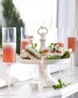 Champagne flutes of pink champagne and crayfish sandwiches on cake stand — Stock Photo