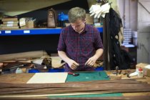 Männlicher Arbeiter in der Lederwerkstatt, der sich Pläne ansieht, um ein Armband herzustellen — Stockfoto