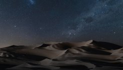 Vista de dunas de arena bajo cielo estrellado nocturno - foto de stock