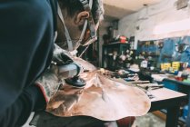Metalworker polishing copper in forge workshop — Stock Photo