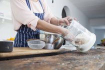 Abgeschnittenes Bild einer Frau, die an der Küchentheke Mehl aus einem Glas schöpft — Stockfoto