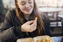 Portrait of young woman, outdoors, eating chips, Bristol, UK — Stock Photo