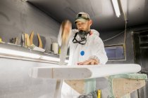 Плотник-мужчина распиливает доску для серфинга в мастерской производителя досок — стоковое фото
