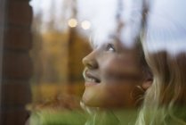 Дівчина з довгим світлим волоссям дивиться вгору через вікно — стокове фото
