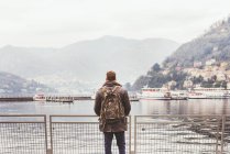Задній вид молодий чоловік на набережній з видом на озеро Комо, Італія — стокове фото