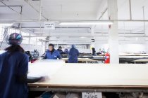 Женщины-работники фабрики разворачивают текстиль на швейной фабрике — стоковое фото