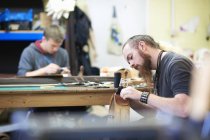 Männlicher Arbeiter in Lederwerkstatt, näht Nähte um eine Gürtelschnalle — Stockfoto