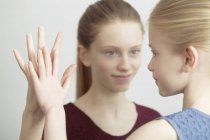 Portrait of two sisters, face to face, touching hands — Stock Photo