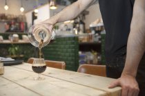 Mâle barista mains verser café noir dans le verre — Photo de stock