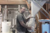 Männlicher Müller füllt Säcke mit gemahlenem Mehl in Weizenmühle — Stockfoto