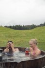 Junges Paar entspannt im ländlichen Whirlpool mit Rosenwein, sattelbergalm, Tirol, Österreich — Stockfoto