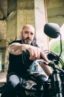 Ritratto di motociclista uomo maturo seduto su moto sotto cavalcavia — Foto stock