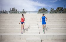 Young male and female runners moving down stairway — Stock Photo