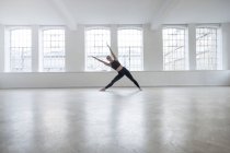 Mujer en estudio de danza inclinándose hacia los lados estirándose - foto de stock