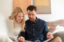 Couple with laptop looking at paperwork at home — Stock Photo