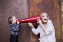 Young boy speaking into megaphone, woman holding megaphone to her ear — Stock Photo
